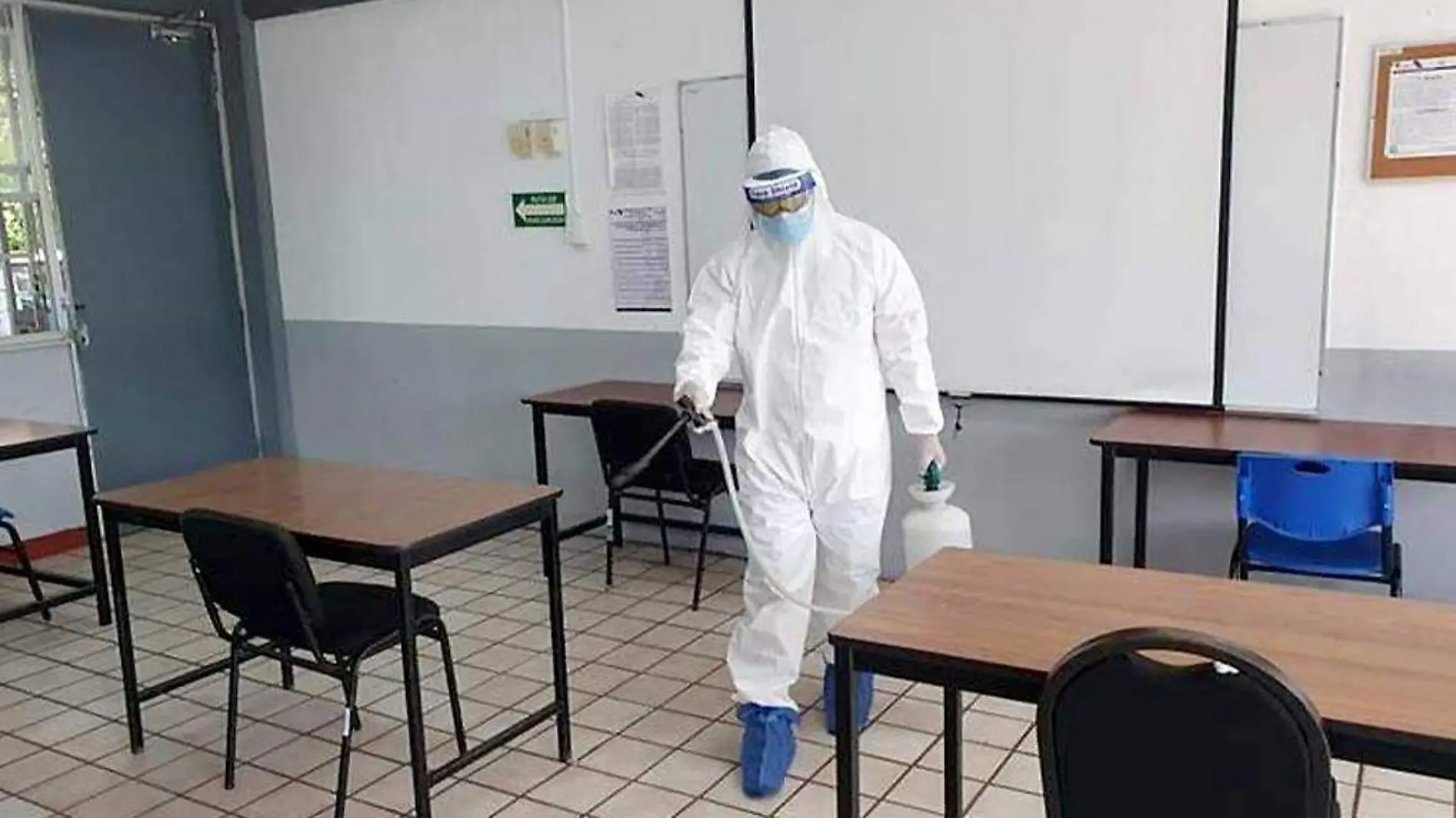 Persona sanitizando salón de clases